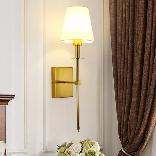 De Aurelia Wall Light in een klassieke gouden afwerking, met een elegante witte lampenkap, voegt een verfijnde uitstraling toe aan elke kamer en biedt sfeervolle verlichting.