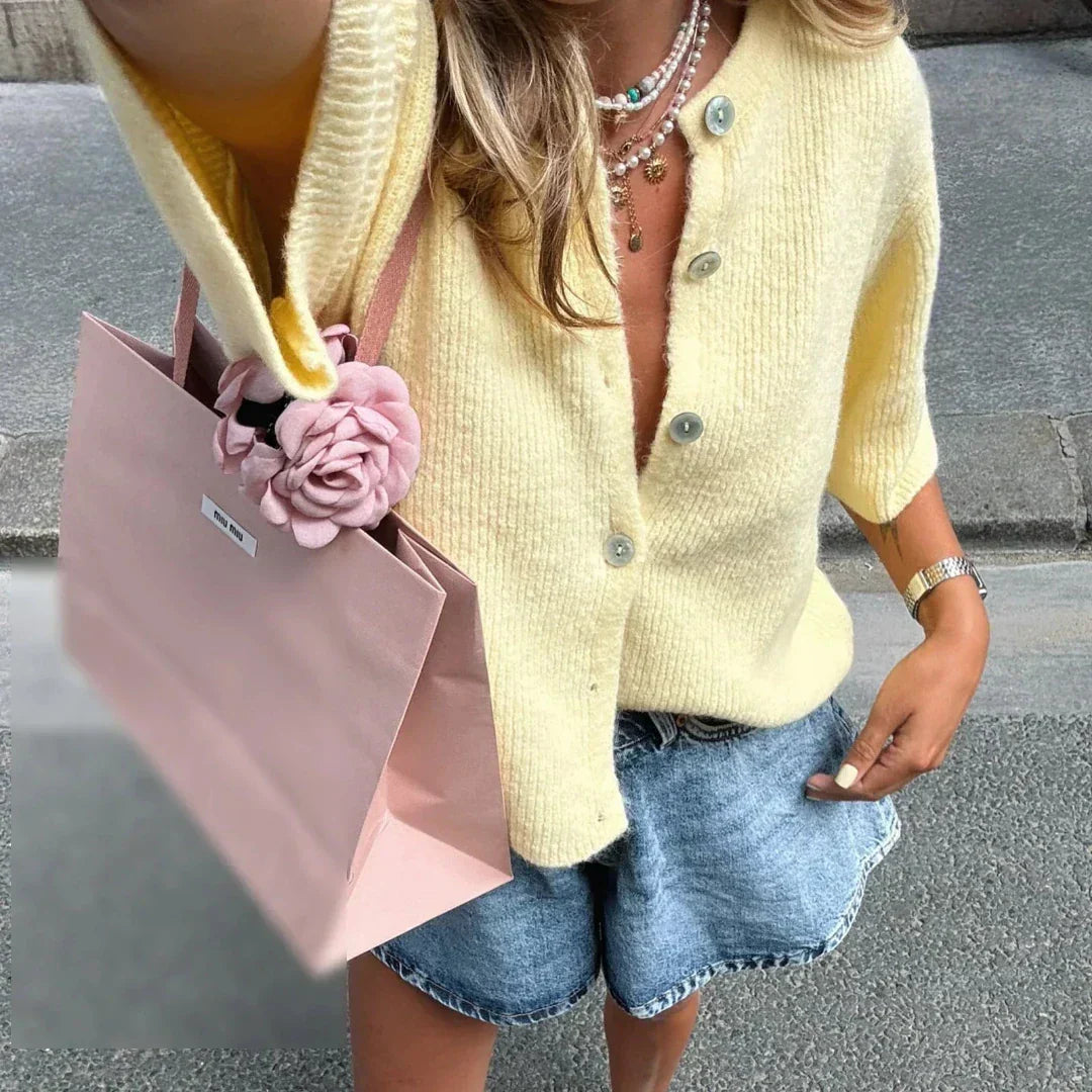 Bellorra vrouwelijk gilet in zachtgeel, met korte mouwen en een tijdloze uitstraling. Het gilet heeft een klassieke knoopsluiting en wordt moeiteloos gecombineerd met denim shorts voor een frisse zomerse look. Perfect voor casual dagen of een stijlvolle wandeling door de stad.