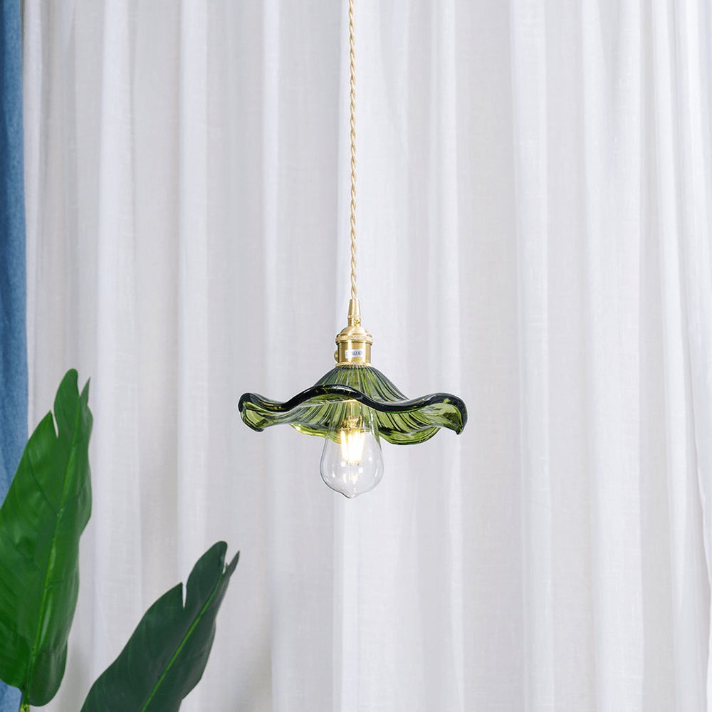 Hanglamp van BloomLume met een sierlijke groene glazen kap en een gouden fitting, ontworpen voor een stijlvolle en natuurlijke uitstraling. Perfect om een warme en uitnodigende sfeer te creëren in woonkamers, eetruimtes of artistieke interieurs. Een elegant accent voor elk modern huis.