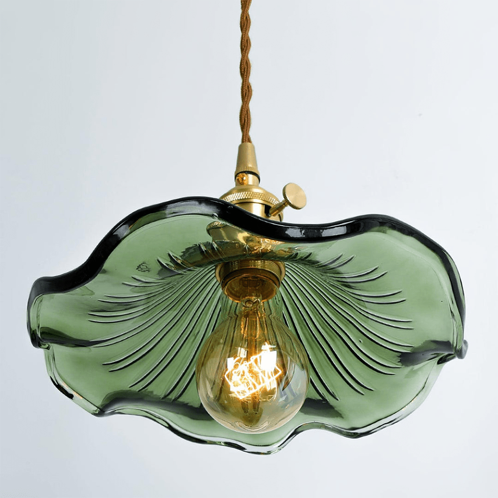 Close-up van de BloomLume hanglamp met een golvende groene glazen kap en een vintage messing fitting. Deze stijlvolle lamp straalt een warme gloed uit dankzij het decoratieve filamentlampje, perfect voor een natuurlijke en elegante uitstraling in elk interieur. Ideaal voor woon- en eetruimtes.