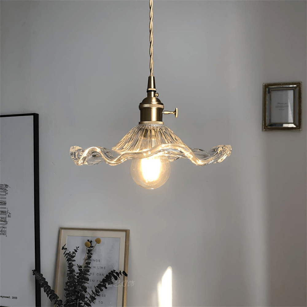 Hanglamp van BloomLume met een transparante golvende glazen kap en een vintage messing fitting. Deze stijlvolle en natuurlijke lamp creëert een zachte en warme gloed, perfect voor een elegante uitstraling in woon- of eetkamers. Een tijdloos ontwerp dat elke ruimte verfraait.