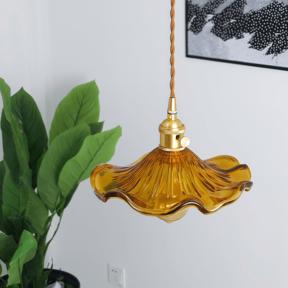 BloomLume hanglamp met een sierlijke amberkleurige glazen kap en een verfijnde gouden fitting. Deze stijlvolle en natuurlijke lamp straalt warmte en elegantie uit, ideaal voor een verfijnde uitstraling in woonkamers, eetruimtes of creatieve interieurs. Een perfecte balans tussen functionaliteit en design.