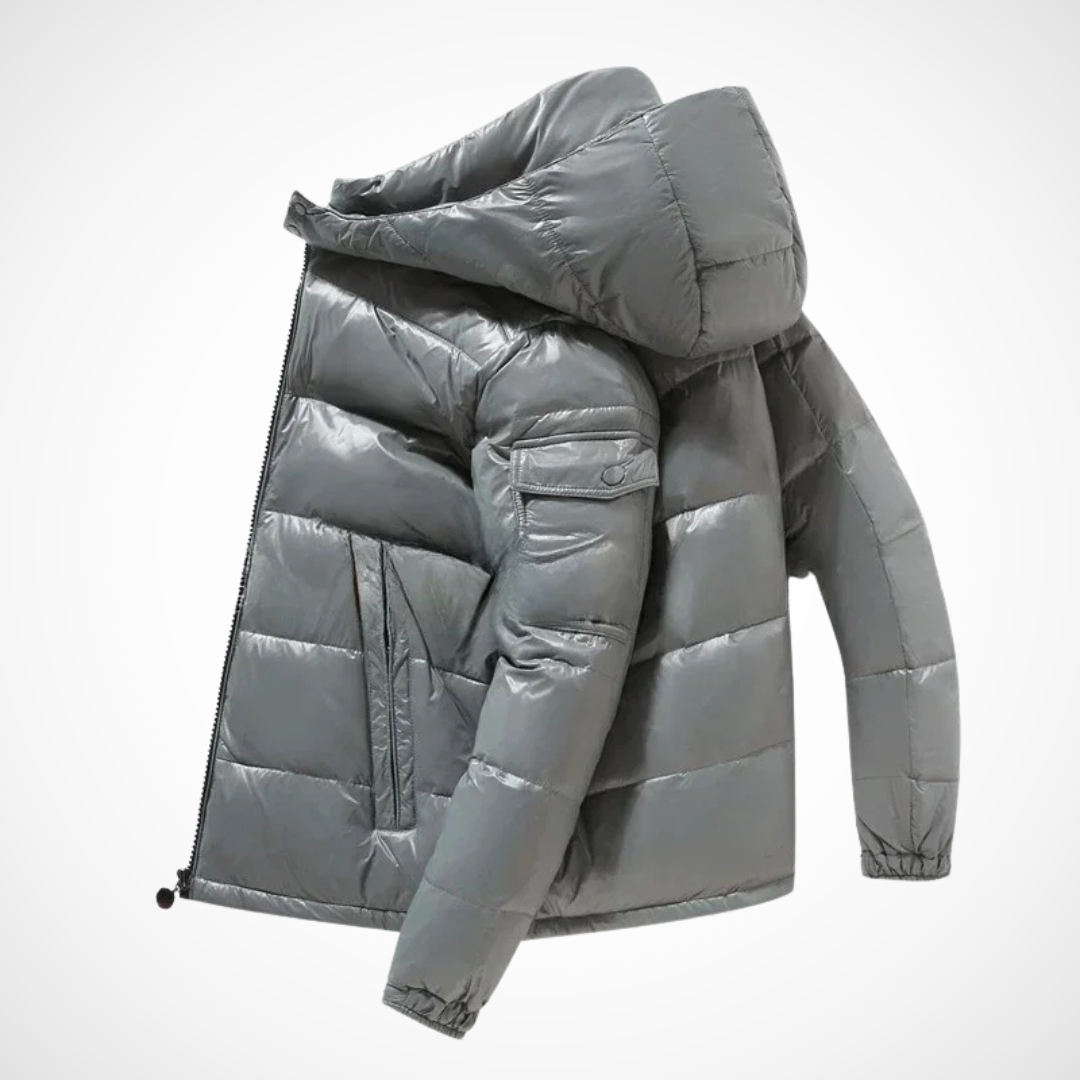 Borstin Winterjas Puffer in stijlvol glanzend grijs. Deze comfortabele, gewatteerde herenjas met capuchon biedt warmte en bescherming tijdens koude winterdagen. Modern ontwerp met praktische zakken.