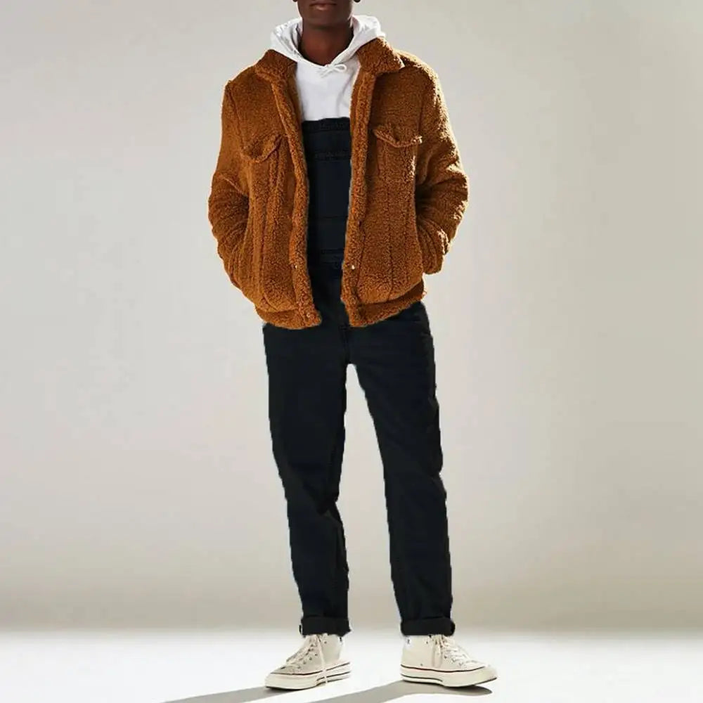 Man draagt een oversized bruine teddyjas over een zwarte denim jumpsuit, gecombineerd met een witte hoodie en sneakers voor een casual en comfortabele uitstraling. Perfect voor een moderne en stijlvolle look in koudere seizoenen.