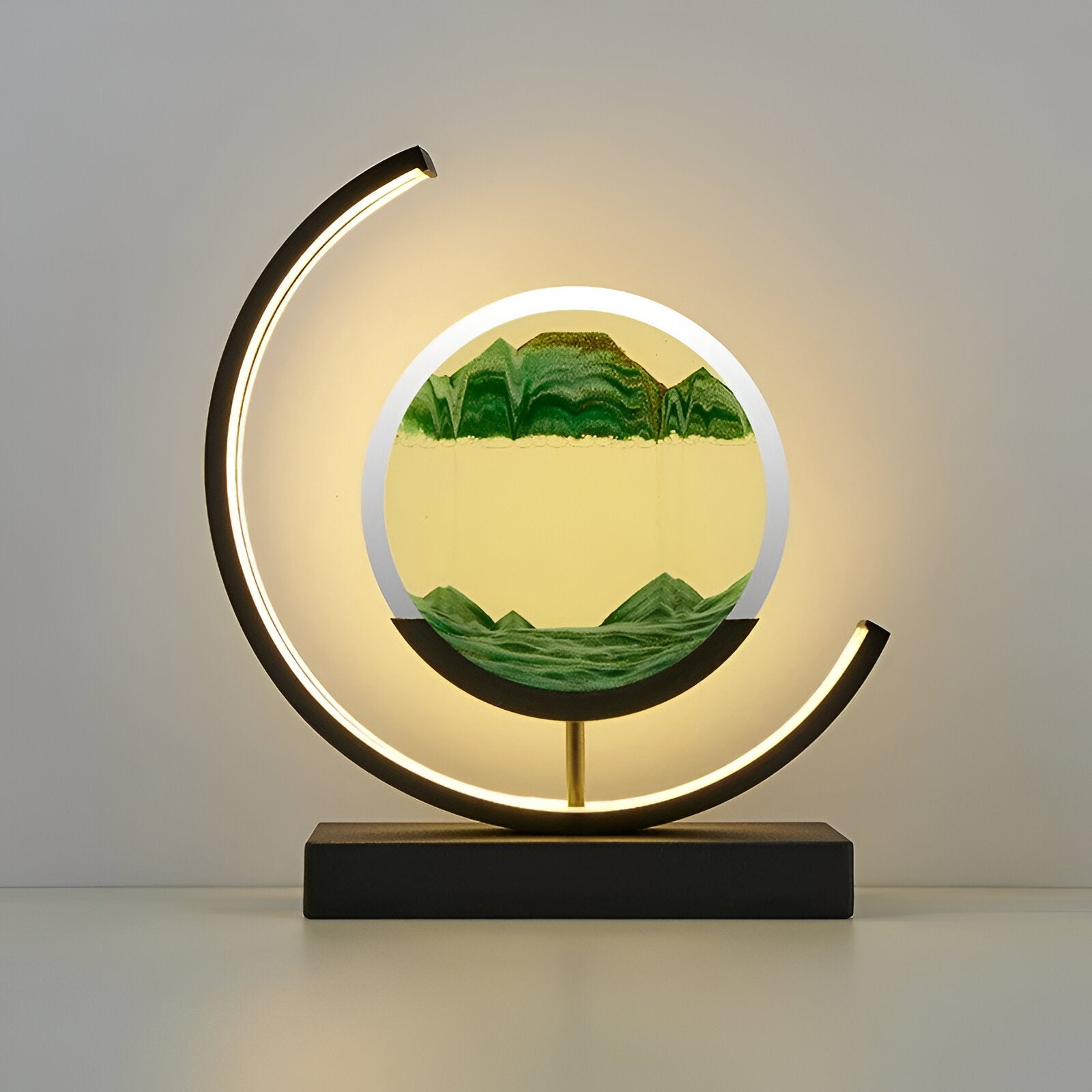 De GlareGlow Sandlamp in groen en geel creëert een rustgevende sfeer met zijn elegante ontwerp. Het lampenkapje bevat dynamisch bewegend zand dat een landschap van bergen en valleien vormt, omgeven door een modern zwart-gouden basis. De zachte verlichting van de lamp zorgt voor een kalmerende en stijlvolle toevoeging aan elk interieur.