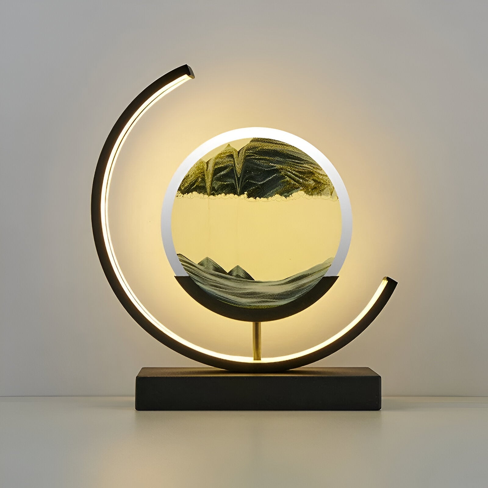 De GlareGlow Sandlamp in groene en gele tinten toont dynamisch bewegend zand dat een bergachtig landschap vormt. Het lampontwerp is voorzien van een moderne zwarte en gouden basis met een cirkelvormige zandlamp en sfeervolle verlichting, perfect voor het creëren van een rustige en stijlvolle sfeer in elk interieur.