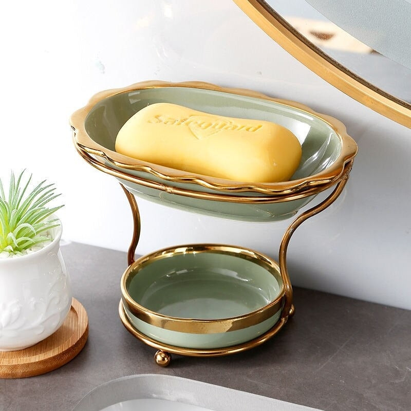 GleamEdge zeepbakje in zachtgroen met gouden accenten, gepresenteerd op een elegante tweelaagse metalen standaard. Dit moderne ontwerp biedt een stijlvolle en praktische oplossing om zeep droog en schoon te houden in de badkamer.