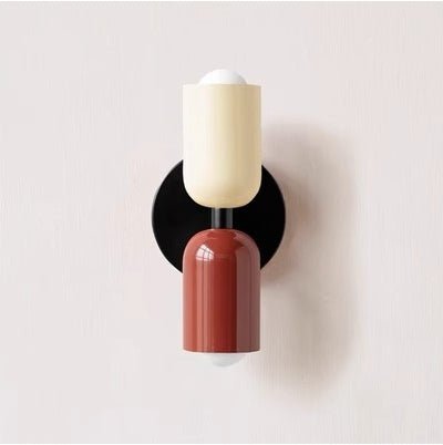 Een Deense stijl wandlamp met een minimalistisch ontwerp, bestaande uit twee cilindervormige lampenkappen in crème en terracotta kleuren, gemonteerd op een zwarte wandbeugel. De lamp biedt een moderne en stijlvolle uitstraling, met een zachte lichtstraal die de ruimte verlicht en een eigentijdse sfeer creëert.