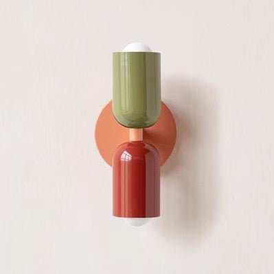 Een Deense stijl wandlamp met een eigentijds ontwerp, featuring een groene en terracotta gekleurde cilindervormige lampenkap bovenop een oranje wandbeugel. Deze lamp combineert moderne kleuren en eenvoudige vormen om een stijlvol statement in de ruimte te maken, terwijl het zachte licht een gezellige sfeer creëert.