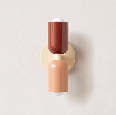 Een Deense stijl wandlamp met een eigentijds design, bestaande uit een combinatie van terracotta en zachtroze lampenkappen, bevestigd aan een gouden wandbeugel. De lamp straalt een warm, uitnodigend licht uit en voegt een moderne, minimalistische flair toe aan elke ruimte.