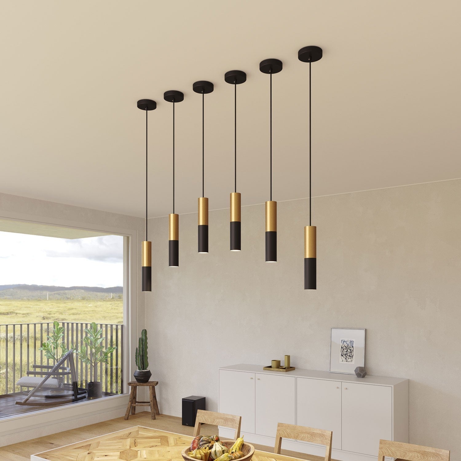 Een reeks van zeven stijlvolle pendellampen in zwart en goud, elegant opgehangen boven een eettafel. De lampen stralen een warme gloed uit en creëren een moderne, verfijnde uitstraling in het interieur, ideaal voor een sfeervolle eetruimte met uitzicht op het landschap.