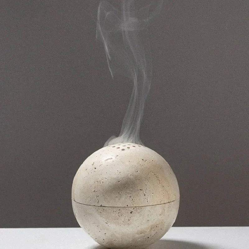 Grazia wierookhouder in een bolvormig, rustgevend ontwerp van natuursteen, met rook die uit de openingen stijgt. Perfect voor het creëren van een kalme en ontspannen sfeer in huis of tijdens meditatie.