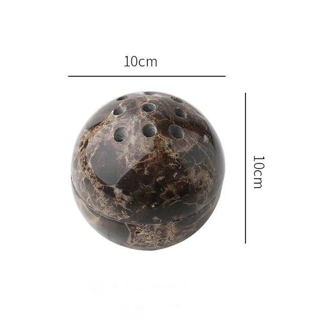 Grazia wierookhouder met rustgevend ontwerp, vervaardigd uit donker marmer met een gepolijste afwerking. De bolvormige houder heeft een diameter van 10 cm en beschikt over meerdere gaten voor wierookstokjes. Ideaal voor een kalmerende sfeer in huis.