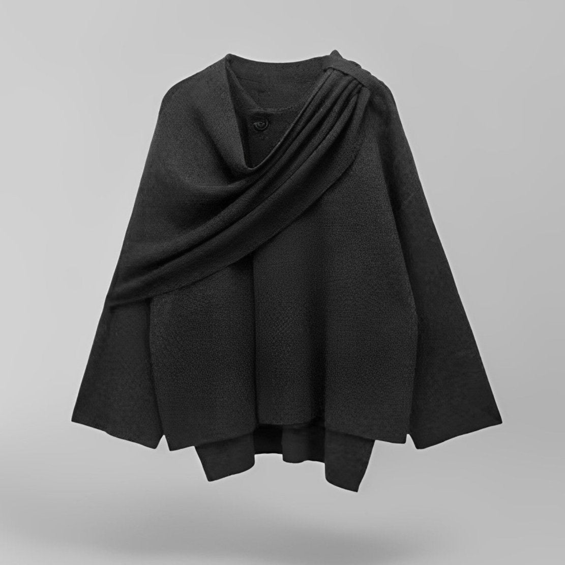 Tijdloze Kallista zwarte cape, met een chique drapering en elegante knoopdetails. Een veelzijdig en verfijnd kledingstuk voor een stijlvolle look.