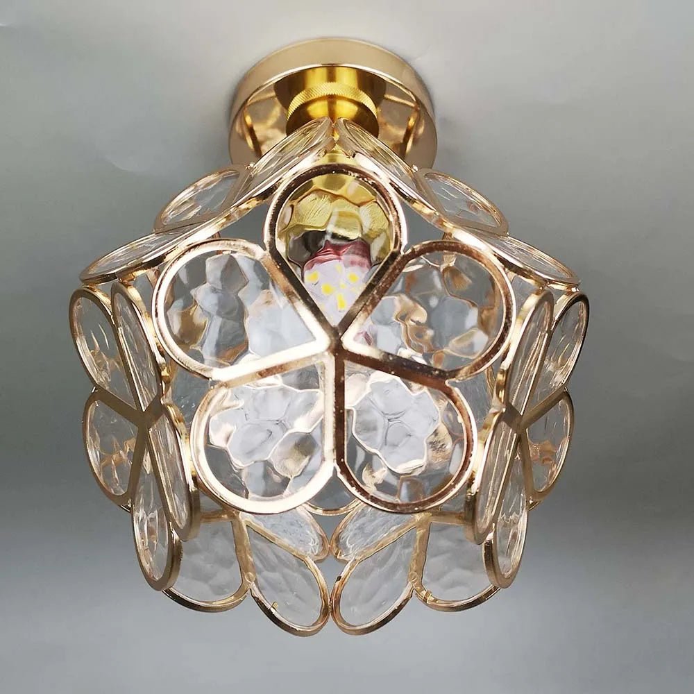 De Lumeera plafondlamp in bloemstijl verenigt gouden accenten en transparante glaselementen in een bloemig ontwerp. Ze zorgt voor zacht, warm licht en geeft elke ruimte een elegante, harmonieuze sfeer.