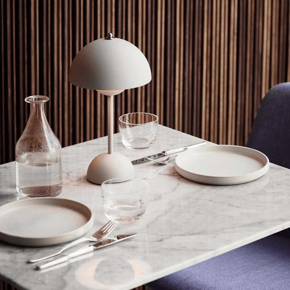 De LumiNova LED-tafellamp in een minimalistisch design, sfeervol geplaatst op een marmeren tafel gedekt met modern servies en glaswerk, ideaal voor stijlvolle eetomgevingen.