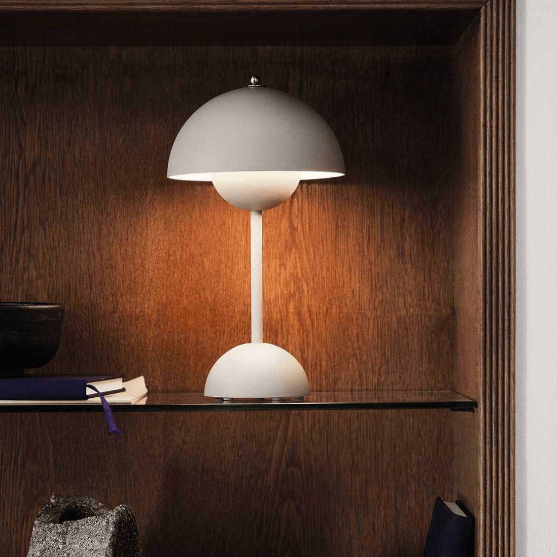 LumiNova LED-tafellamp met modern design, sfeervol verlicht en geplaatst op een glazen plank in een houten kast, perfect als accentverlichting in een stijlvolle ruimte.