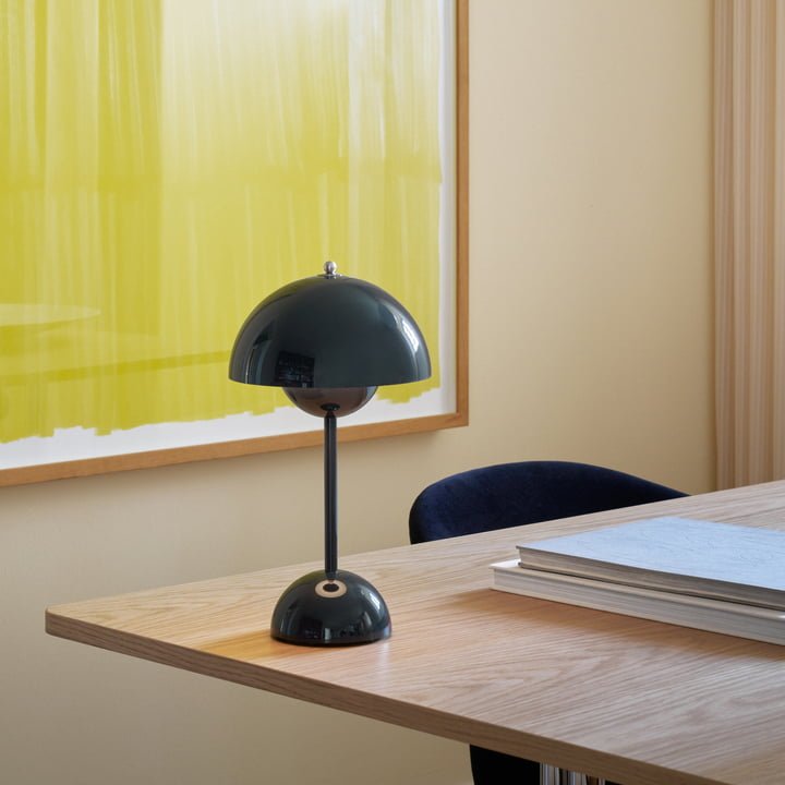 Een moderne LumiNova tafellamp in diepe groene kleur, geplaatst op een houten bureau. De lamp heeft een minimalistische, ronde basis en een halfronde kap die een zachte verlichting verspreidt. Perfect voor een stijlvolle en eigentijdse uitstraling in een werk- of woonruimte.
