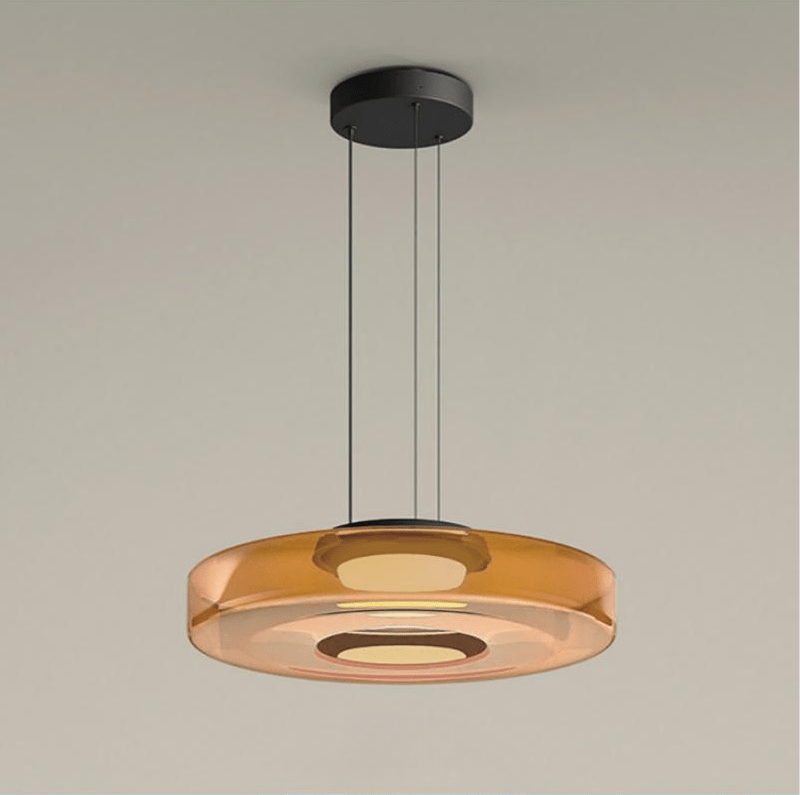 Deze strakke, moderne Bauhaus hanglamp met een enkele amberkleurige glazen schijf creëert een stijlvolle en minimalistische uitstraling. Het elegante ontwerp, met zijn heldere lijnen en subtiele kleuren, is perfect voor een eigentijdse ruimte. De lamp biedt een verfijnde verlichting die de ruimte verrijkt, ideaal voor moderne woonkamers of eetruimtes.