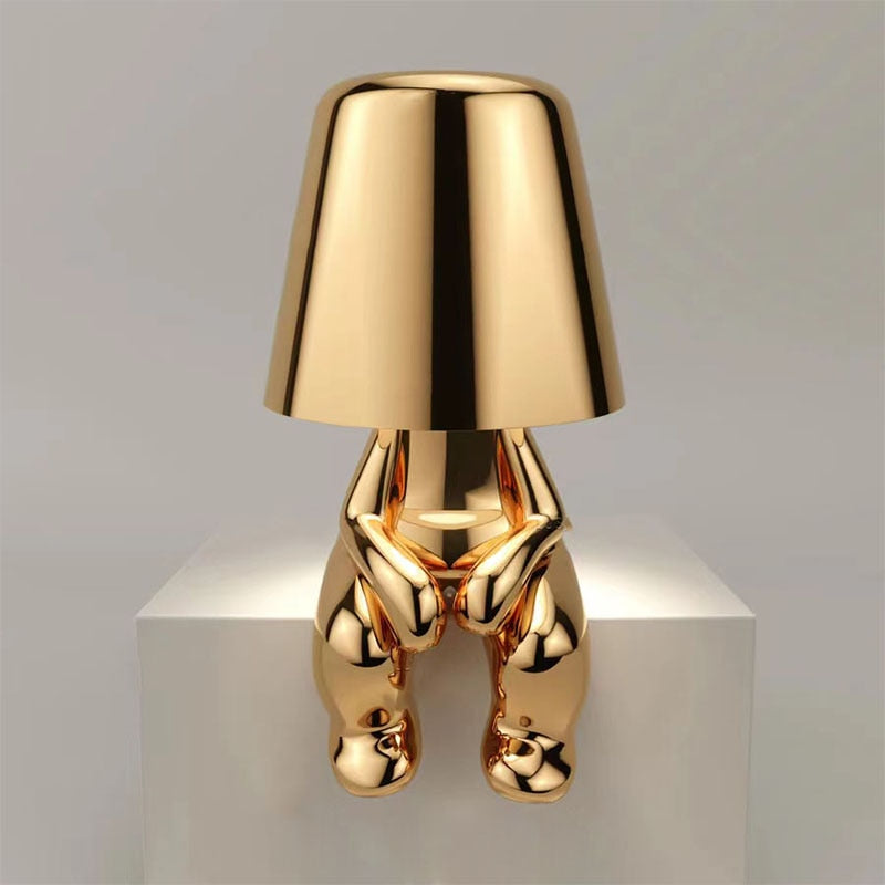 Unieke gouden Lumineer tafellamp met een speels en modern design, perfect voor flexibele verlichting en een stijlvol accent in elk interieur.