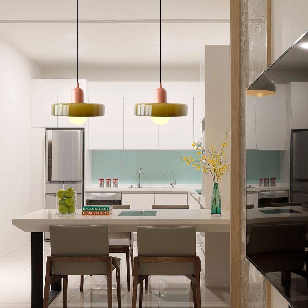 Een moderne keuken met twee kleurrijke Luminezza Living hanglampen met een uniek design. De lampen hebben een eigentijdse uitstraling en hangen boven een witte eettafel met vier stoelen, waarbij het kleurrijke ontwerp warmte en stijl toevoegt aan de ruimte. Perfect voor een trendy interieur.