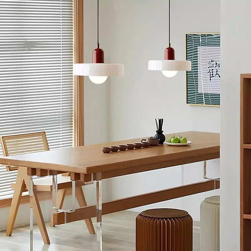 Eetkamer met Luminezza Living hanglampen in kleurrijk design, voorzien van witte kappen en rode fittingen. Stijlvolle verlichting die warmte en moderniteit toevoegt aan een gezellige ruimte.