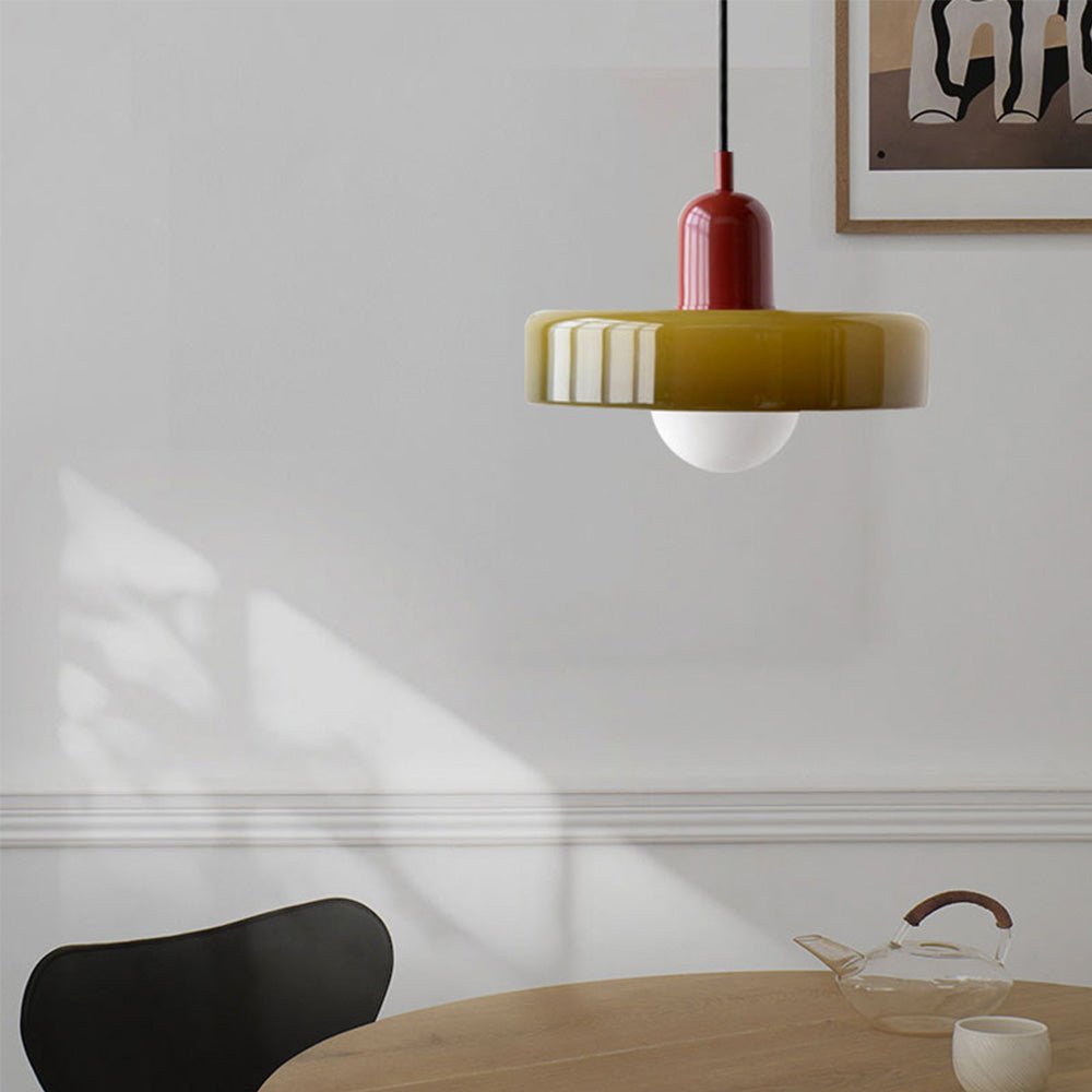 Een stijlvolle close-up van de Luminezza Living hanglamp in een kleurrijk en modern design. De lamp hangt boven een ronde houten tafel met een minimalistische theeset, terwijl de unieke geel-rode tinten warmte en elegantie toevoegen aan het interieur. Perfect voor een trendy en eigentijdse woonruimte.