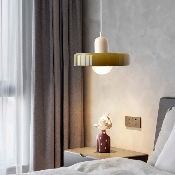 Een moderne slaapkamer met de Luminezza Living hanglamp in kleurrijk design, met een glanzend geelgroene kap en een crème-witte bovenkant. De lamp hangt boven een nachtkastje met een decoratieve vaas, en voegt een warme en stijlvolle uitstraling toe aan de ruimte. Perfect voor een eigentijdse en gezellige sfeer.