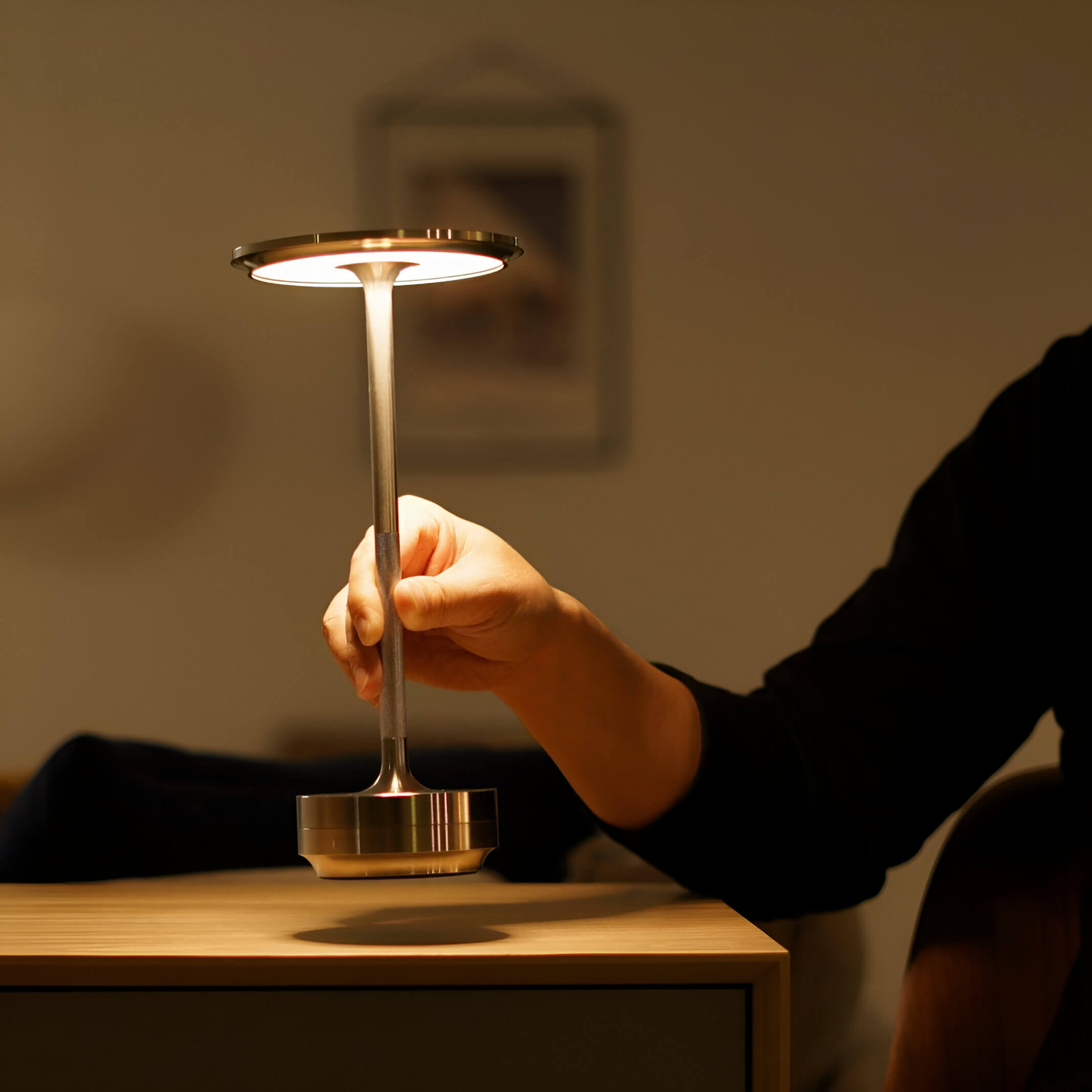 Oasa Mood Light draadloze en oplaadbare lamp in gebruik, met een hand die de lamp aanraakt, geplaatst op een houten tafel.