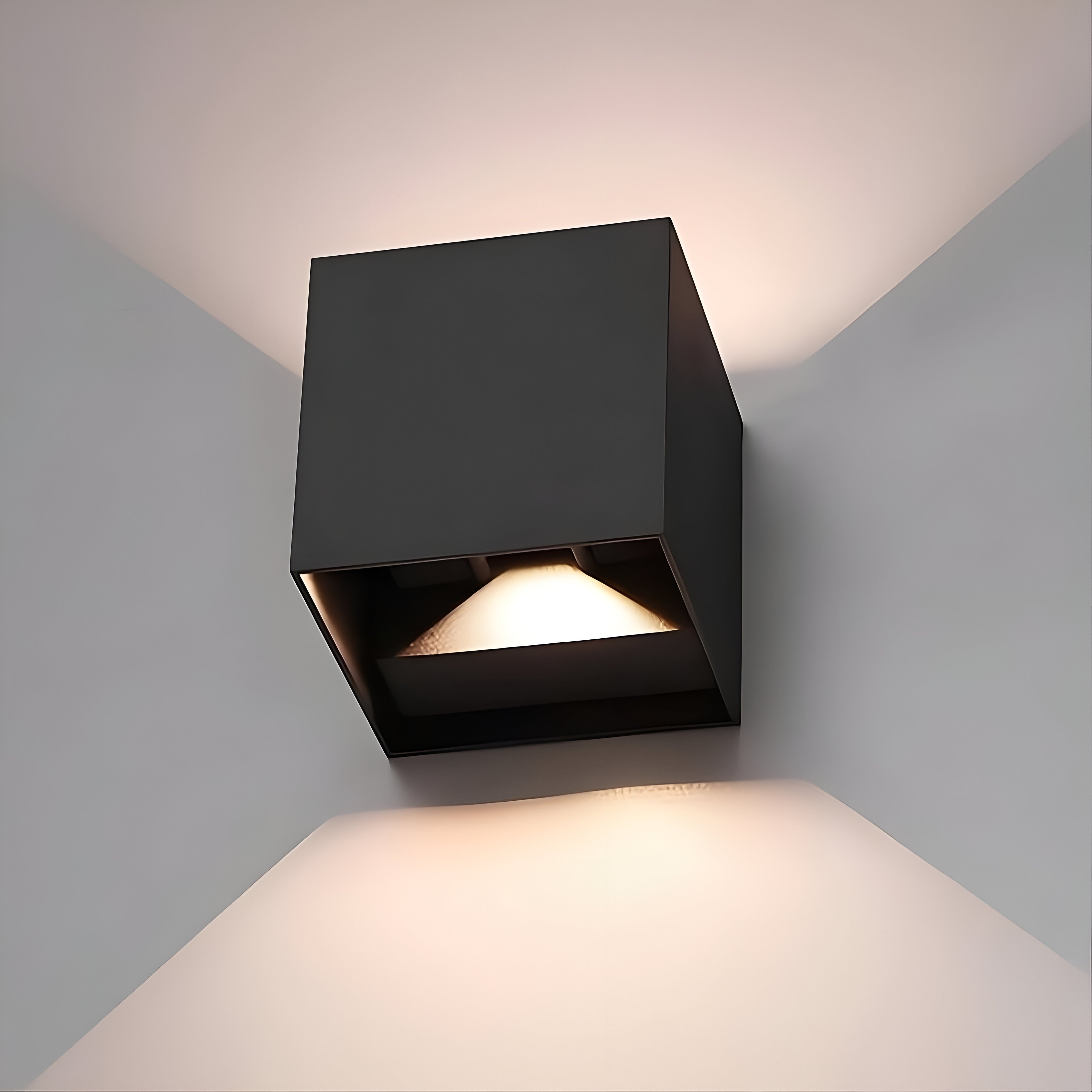 Omnira Glow verstelbare wandlamp in zwart, gemonteerd op een hoek van de muur, met een zacht uitgestreken licht naar boven en beneden.