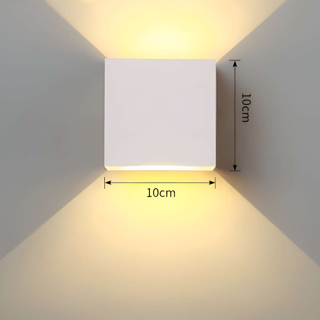 Omnira Glow verstelbare wandlamp in wit met afmetingen van 10 cm breed en 10 cm hoog, schijnt warm licht naar boven en beneden op een lichte muur.