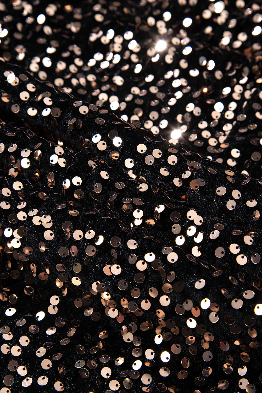 Detailopname van de zwarte feestjurk van Orabella, bedekt met glinsterende pailletten in roségouden tinten. Het luxe ontwerp weerspiegelt het licht prachtig en geeft een verfijnde uitstraling voor een glamoureuze gelegenheid.