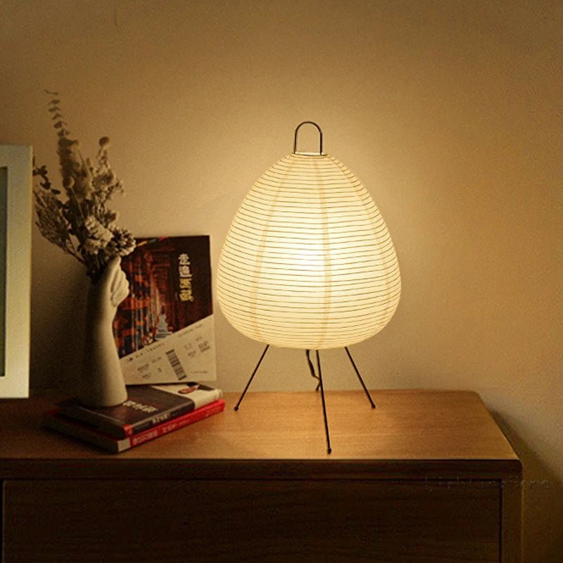 De Prana lamp straalt een warme, zachte gloed uit met zijn gestroomlijnde, ovale papieren lampenkap, ondersteund door een minimalistische metalen standaard. De lamp voegt een elegante en rustige sfeer toe aan elke ruimte, perfect voor het creëren van een gezellige omgeving.
