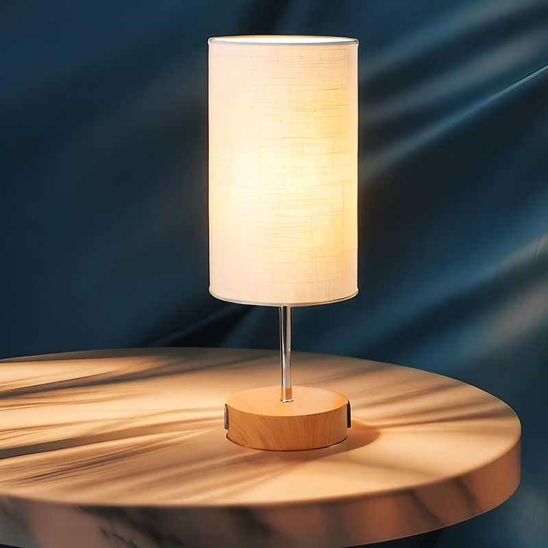 Solvani bedlamp met een moderne en sfeervolle uitstraling. De lamp heeft een cilindervormige witte kap en een houten voet, perfect voor een warme en gezellige sfeer in de slaapkamer of woonkamer. Tijdloos design dat past in diverse interieurstijlen.