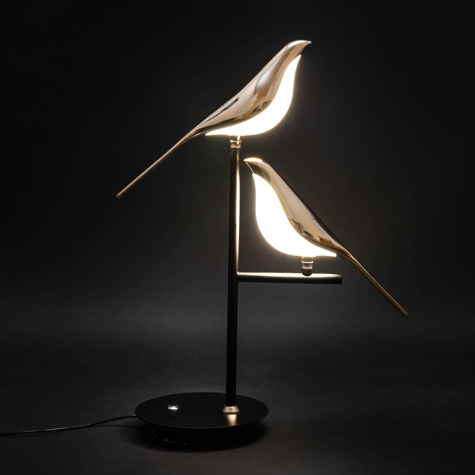 Sprankelum LED Tafellamp Moderne verlichting met twee goudkleurige vogelontwerpen op een zwart metalen voet. De elegante vogels geven sfeervol licht, perfect voor het creëren van een verfijnde ambiance in elke ruimte.