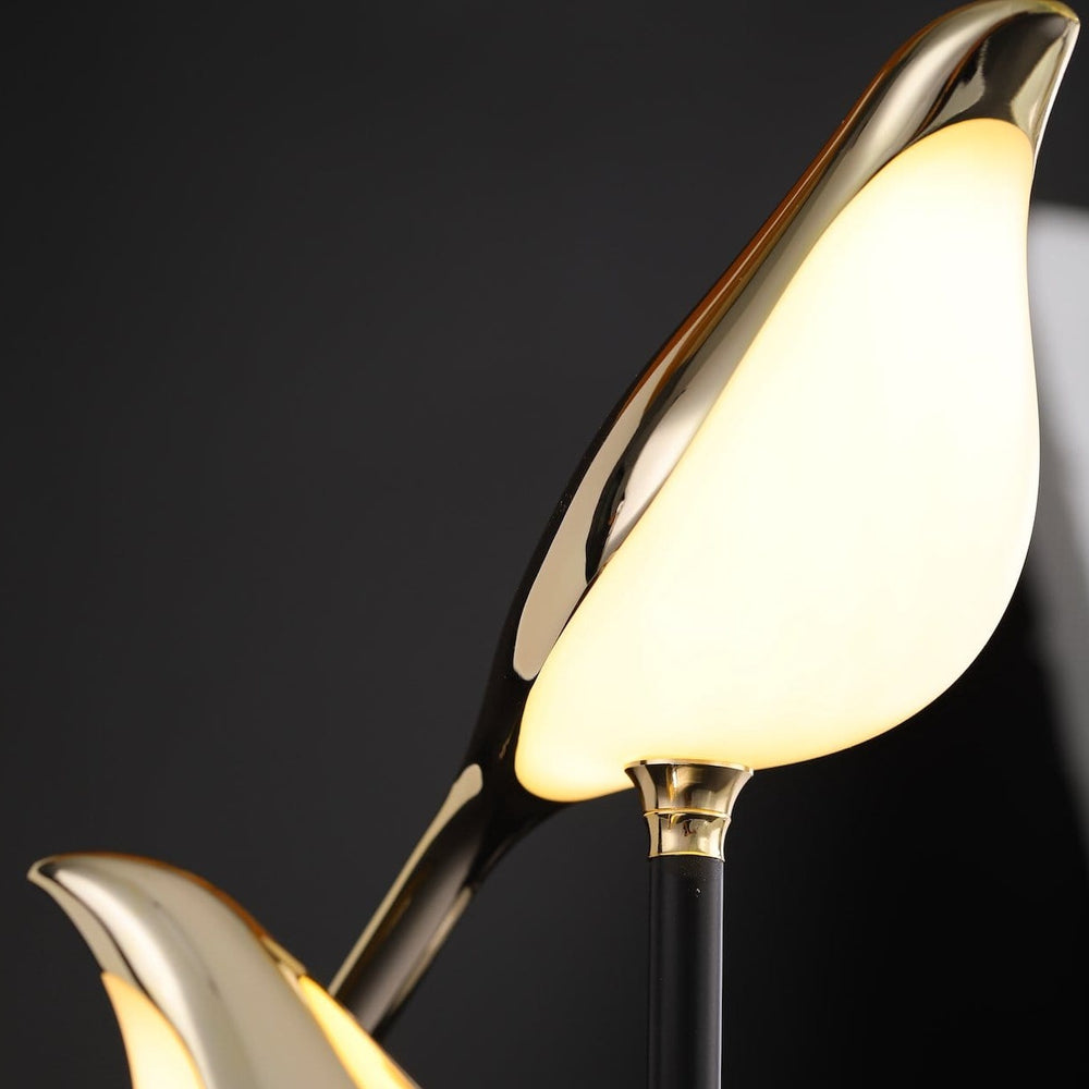 Close-up of the Sprankelum LED Tafellamp, featuring the elegant gold-colored bird-shaped light fixtures that emit a soft, ambient glow. The sleek design highlights the modern fusion of art and functionality, perfect for adding a sophisticated touch to any space.