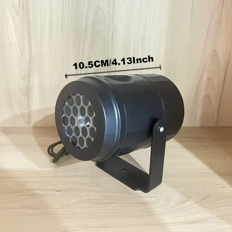 Torenza sneeuwvlok projector, met een zwart apparaat dat op een statief is bevestigd. De projector heeft een diameter van 10,5 cm (4,13 inch) en is gericht op een houten achtergrond, ideaal voor het creëren van winterse sneeuwvlokprojecties in de buitenlucht.