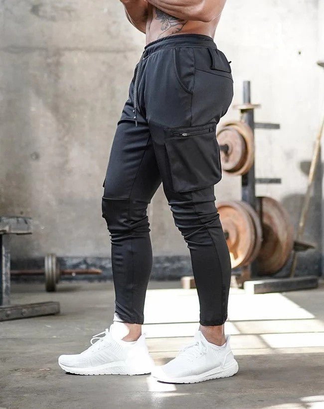 Afbeelding van de Umiro cargo jogger in een strak zwarte kleur. Deze sportieve en comfortabele jogger heeft een slim-fit pasvorm met ruime cargozakken aan de zijkant voor extra functionaliteit en stijl. De elastische tailleband met trekkoord zorgt voor een ideale pasvorm, terwijl het hoogwaardige materiaal flexibiliteit en draagcomfort biedt. Perfect voor workouts of casual outfits.