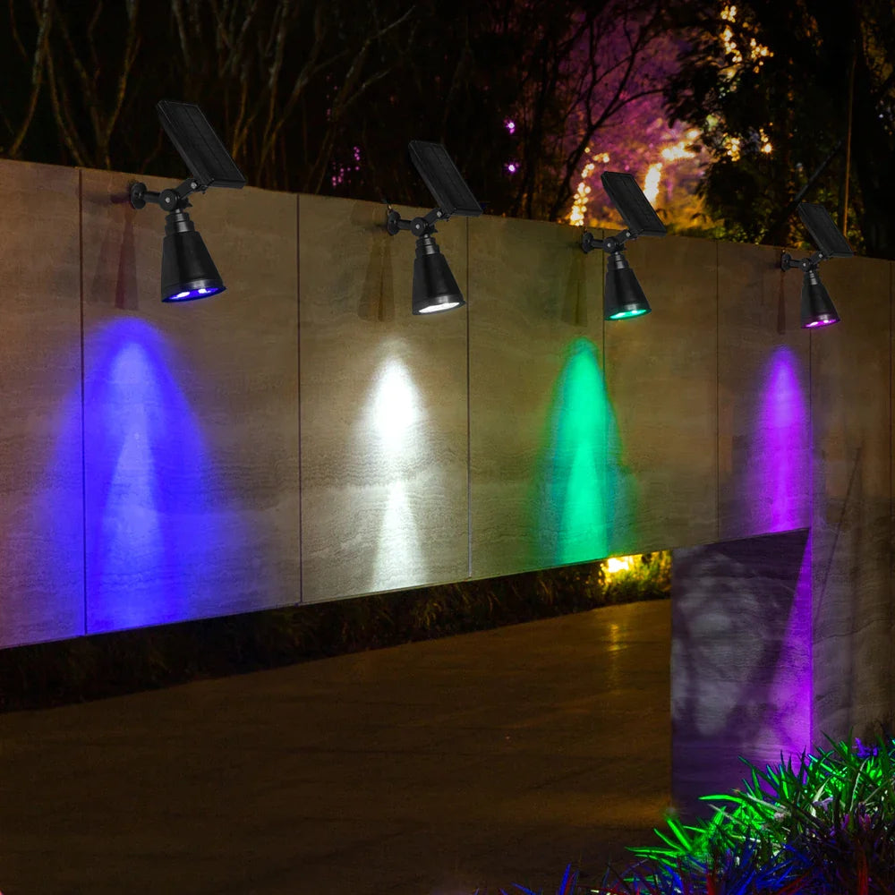 Een set van vier energiezuinige tuinlampen, elk met een zonnepaneel en meerdere kleurinstellingen, die een muur verlichten in verschillende tinten zoals wit, groen, blauw en paars. Deze lampen zijn ideaal voor het verlichten van tuinen, terrassen of opritten en bieden een sfeervolle, energie-efficiënte verlichting.