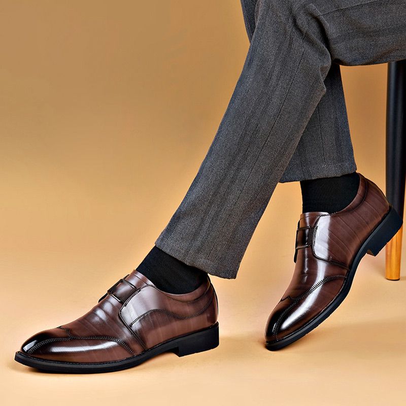 Elegante bruine leren herenschoenen met een klassieke dubbele gesp, gedragen met een grijze broek. Deze stijlvolle schoenen bieden een verfijnde uitstraling en zijn perfect voor formele of zakelijke gelegenheden.
