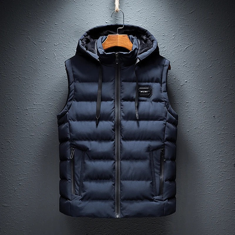 Een gewatteerde bodywarmer van ZachtKern in donkerblauw, met een capuchon en praktische zakken. Dit vest biedt zowel comfort als stijl, perfect voor een casual en modieuze look tijdens de koudere maanden.
