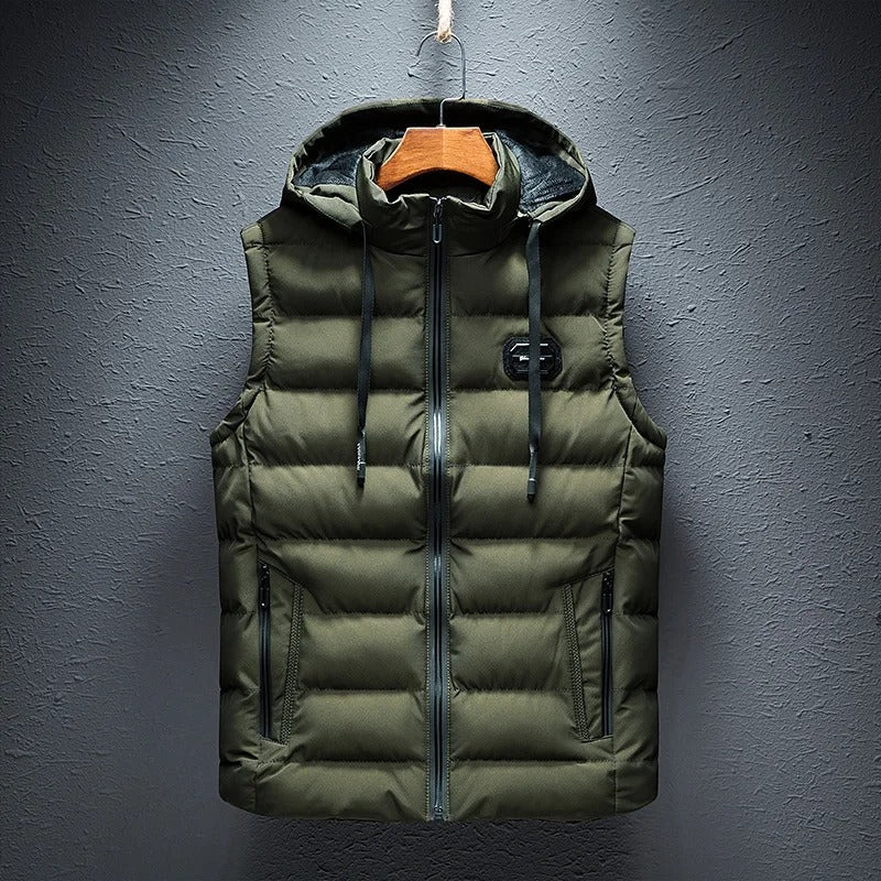 Een gewatteerde bodywarmer van ZachtKern in olijfgroen, met een capuchon en handige zakken. Dit vest biedt comfort en stijl, ideaal voor een casual look tijdens koudere dagen.