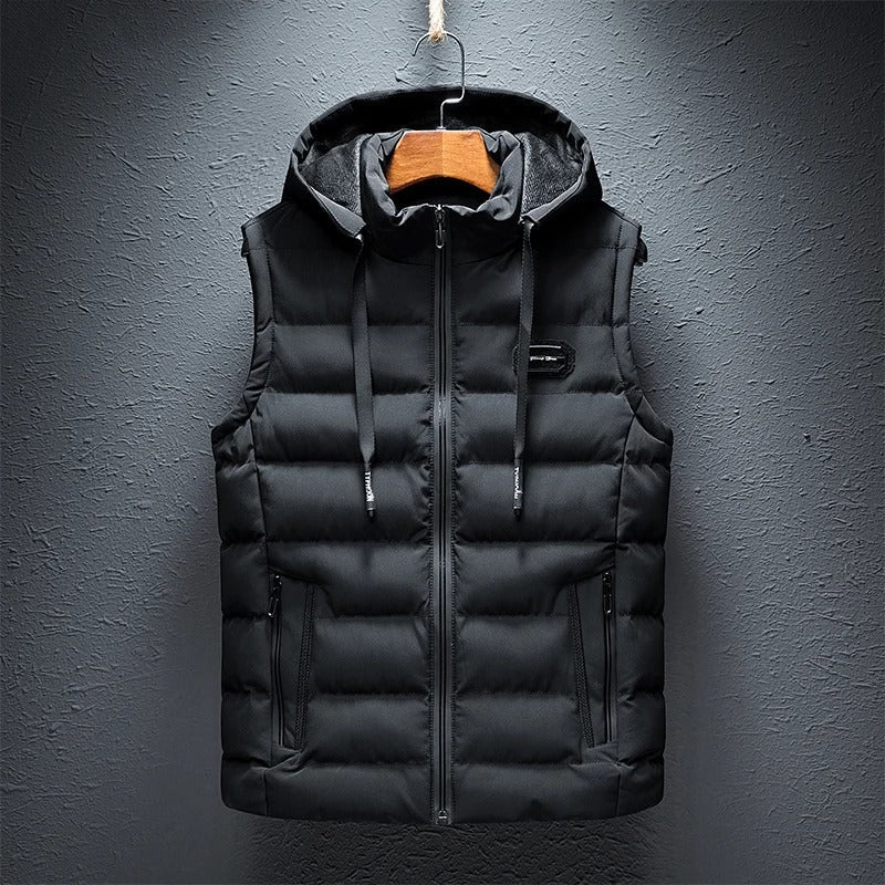 Een gewatteerde bodywarmer van ZachtKern in klassiek zwart, met een capuchon en praktische zakken. Dit vest combineert comfort en stijl, ideaal voor een casual look tijdens de koudere maanden.