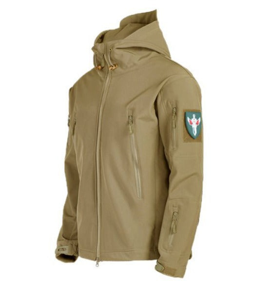 Een zandkleurige waterdichte regenjas met een capuchon en meerdere ritszakken, inclusief een militair geïnspireerd embleem op de mouw. De jas biedt zowel praktische functionaliteit als een stijlvolle uitstraling, ideaal voor het weer en avontuurlijke buitenactiviteiten.