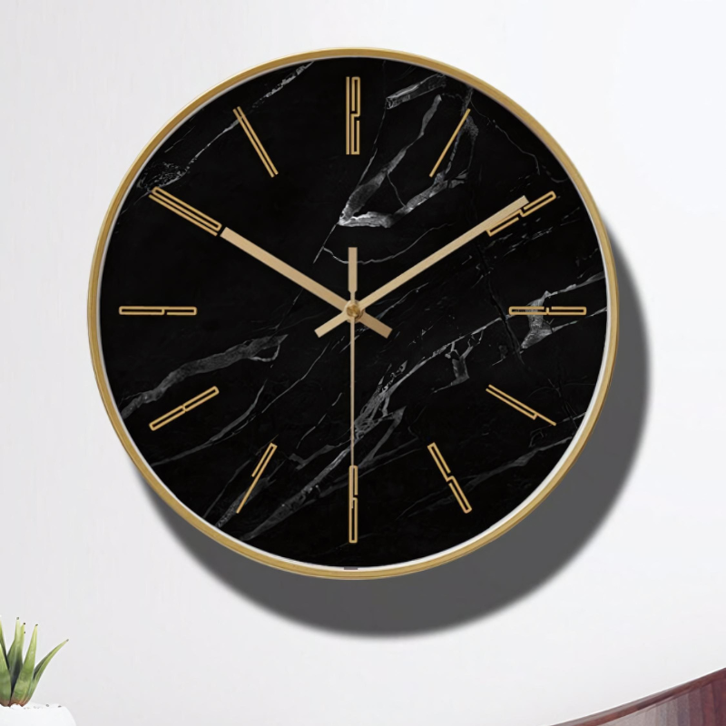 Een elegante Zerano wandklok met een zwarte marmeren wijzerplaat en gouden accenten. De klok heeft een minimalistisch design met slanke gouden wijzers en strepen als uurmarkeringen. Perfect voor een stijlvol interieur.