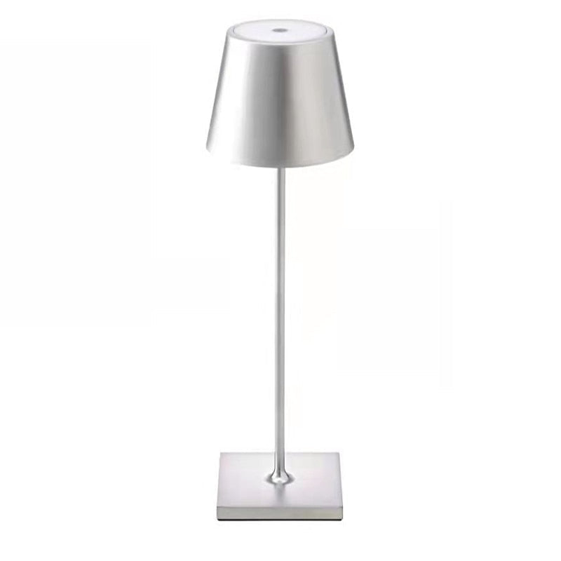 Een moderne, zilveren draadloze tafellamp met een slanke, minimalistische voet en een breed conisch lampenkapje. Het strakke ontwerp voegt een verfijnde, eigentijdse uitstraling toe aan elke ruimte.