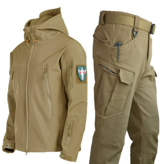 Een beige waterdichte regenjas met bijpassende broek, ontworpen voor ultieme functionaliteit en stijl. De jas heeft een capuchon en meerdere ritszakken voor praktische opbergruimte, terwijl de broek een comfortabele pasvorm biedt met extra zakken voor gemak. Perfect voor buitenactiviteiten en bescherming tegen regenachtige omstandigheden.