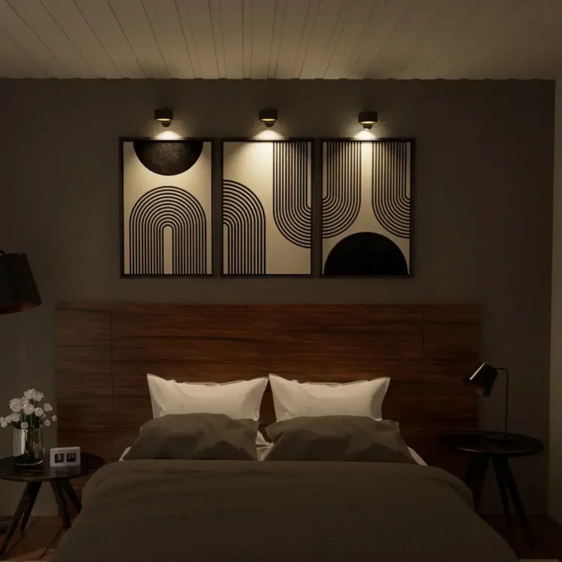 Sfeervolle slaapkamer verlicht door Aurora Glow draadloze wandlampen. De minimalistische zwarte lampen accentueren de wanddecoratie met een warme, gerichte lichtbundel, wat zorgt voor een elegante en moderne ambiance. Perfect voor functionele en decoratieve verlichting in elke slaapkamer.