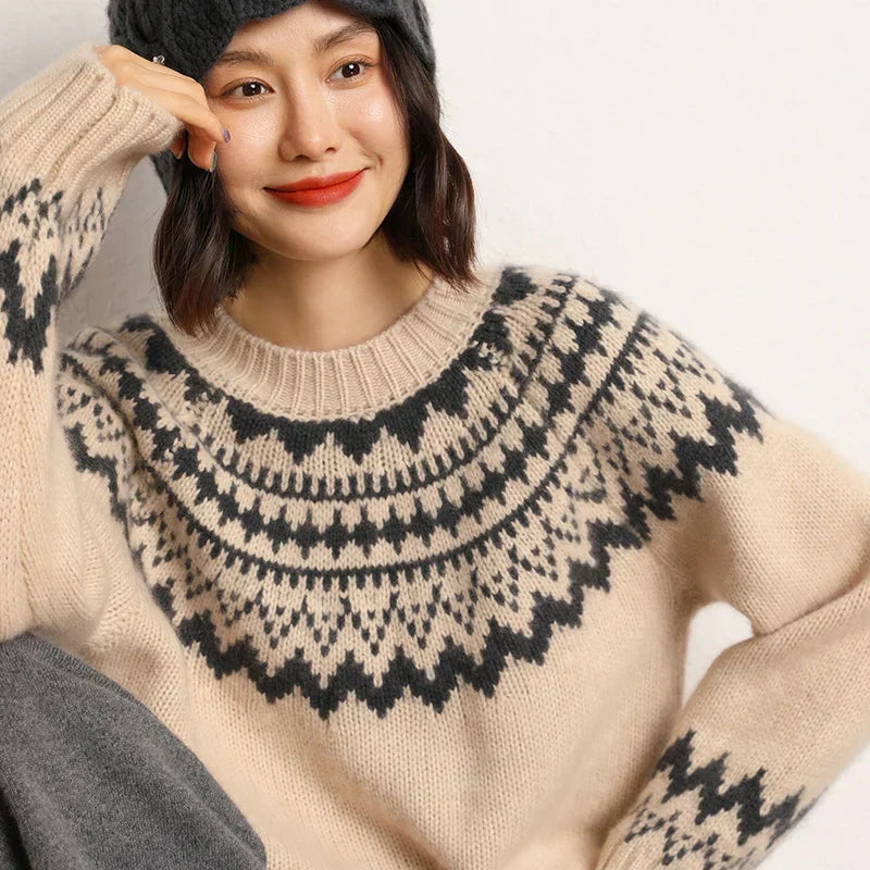 Model draagt een GloVibe trui in beige met een zwart geometrisch patroon. De trui heeft een comfortabele pasvorm, ronde hals en lange mouwen met geribbelde boorden. Perfect voor een moderne en warme look tijdens de koude dagen.