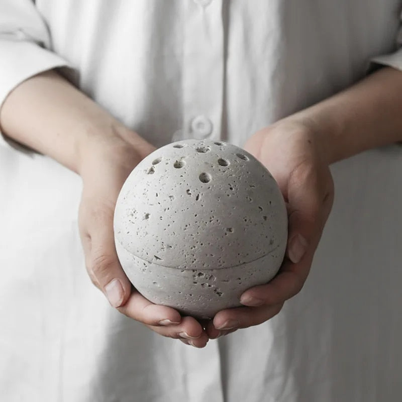 Grazia wierookhouder met rustgevend ontwerp, vastgehouden door een persoon in witte kleding. De ronde, stenen houder heeft meerdere gaten voor wierookstokjes en straalt eenvoud en sereniteit uit. Perfect voor ontspanning en meditatie in elke ruimte.